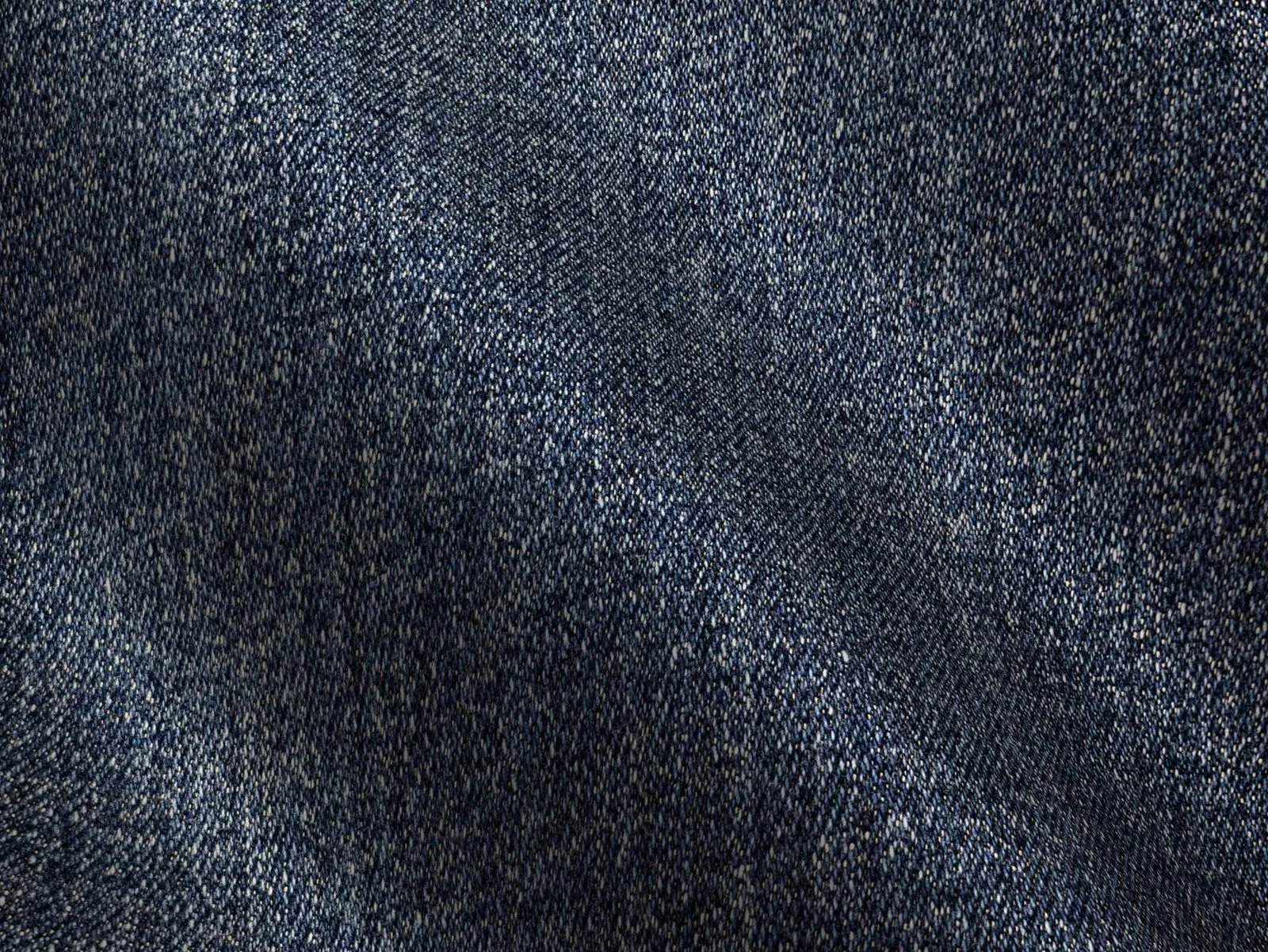 Detailed texture of blue denim fabric with visible grain and folds.